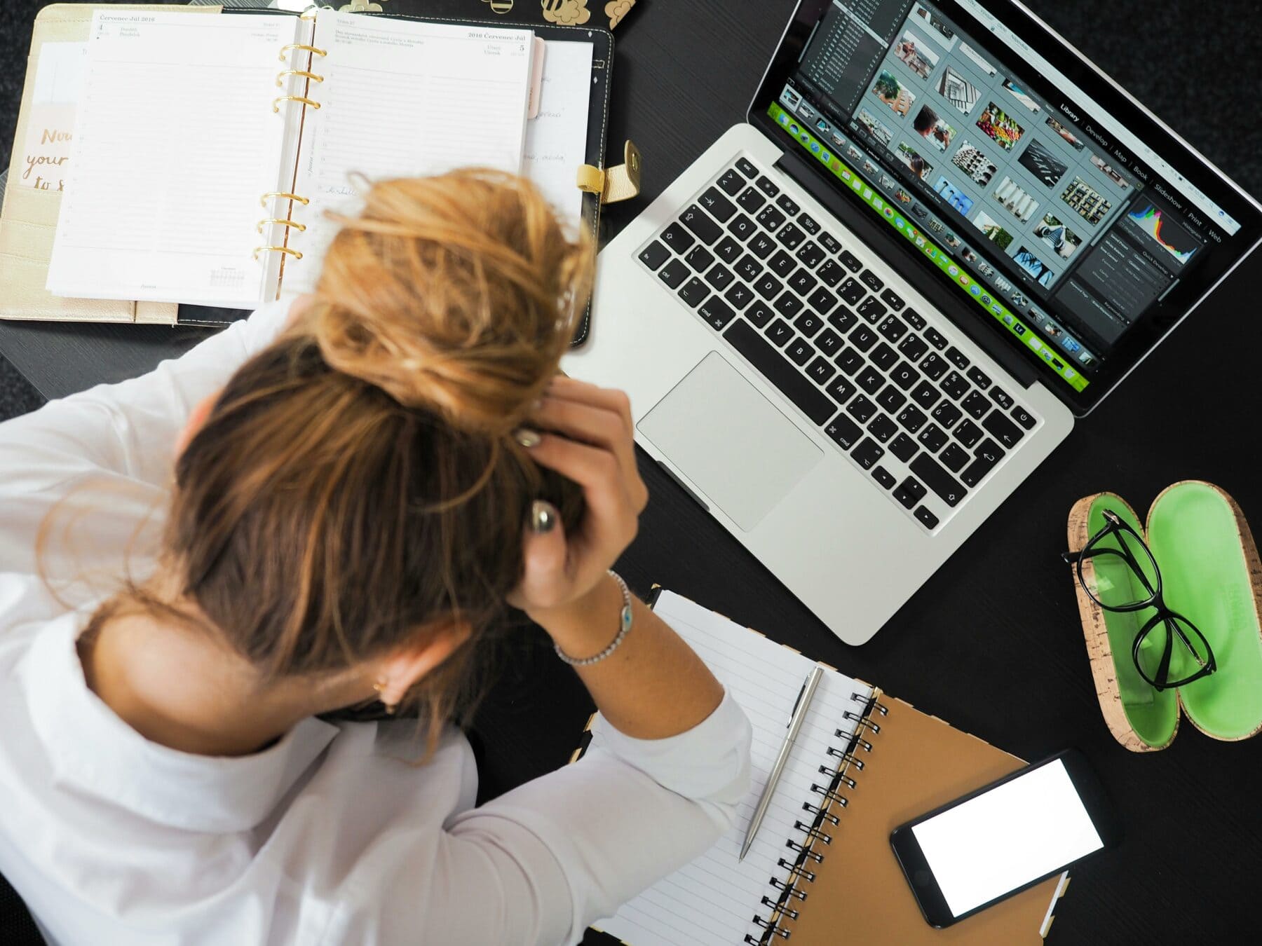 Overwhelmed business leader with a cluttered desk holding her head